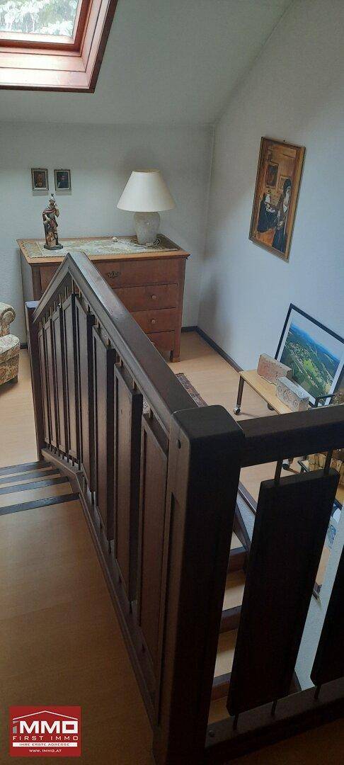 Treppenaufgang mit Holzgeländer und Dachfenster, das den Bereich erhellt.