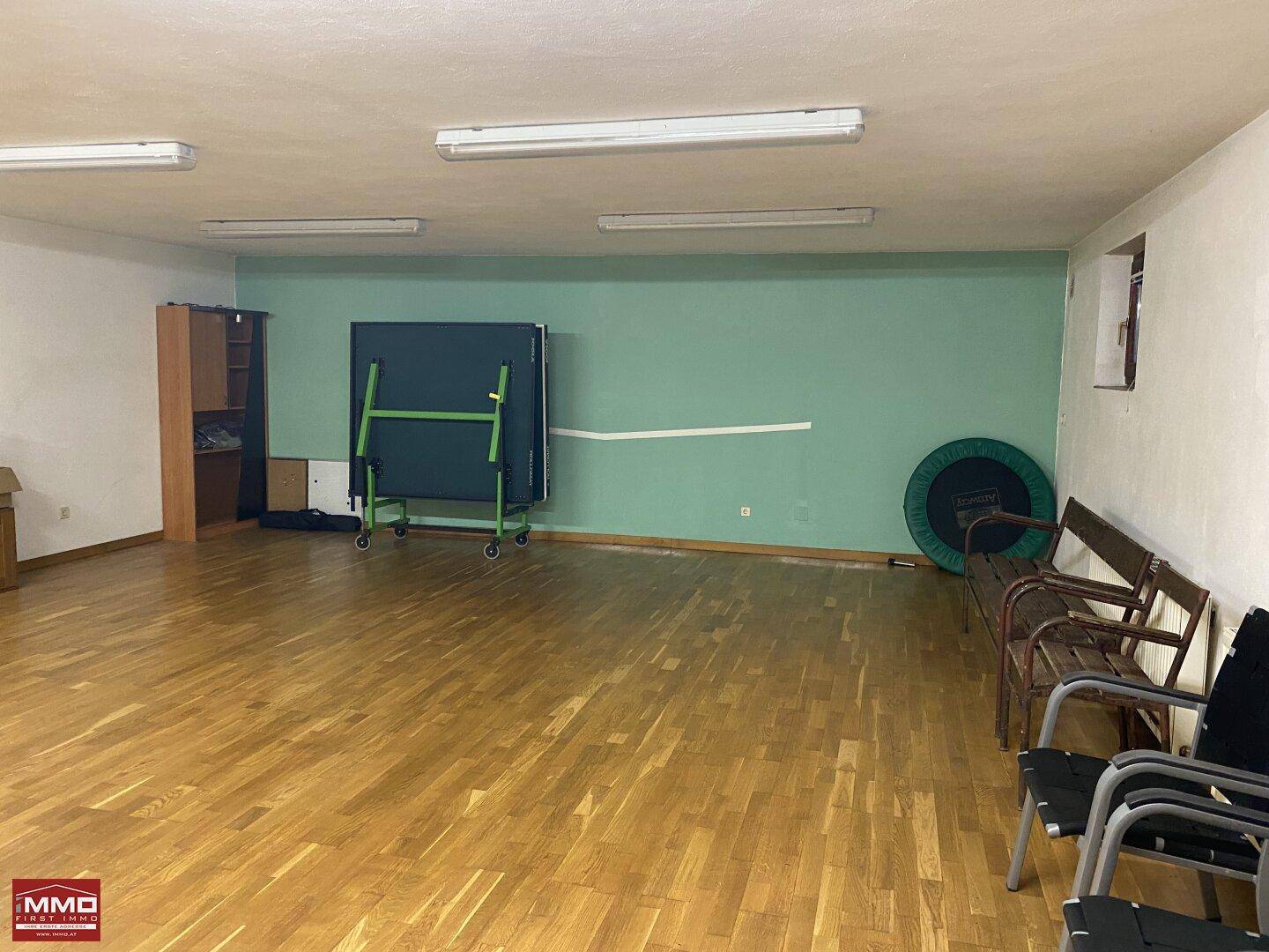 Geräumiger Freizeitraum mit Tischtennisplatte, Sitzbänken und Stauraum.