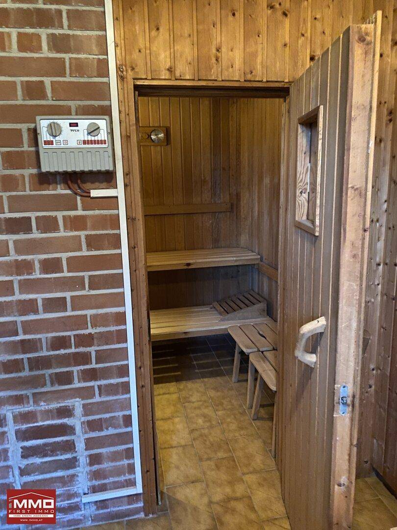 Eingangsbereich einer Holzsauna mit Steuerungselementen und Ziegelwand.