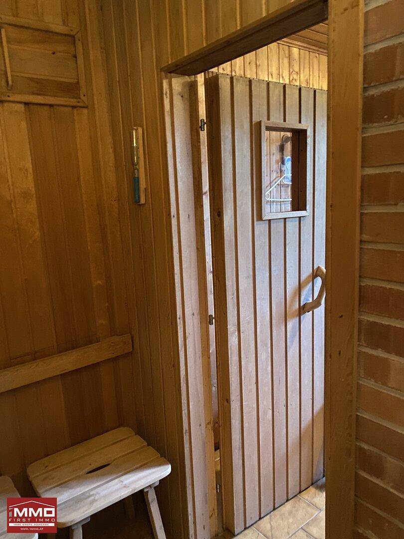 Holztür einer Sauna mit kleinem Fenster und rustikalem Griff.