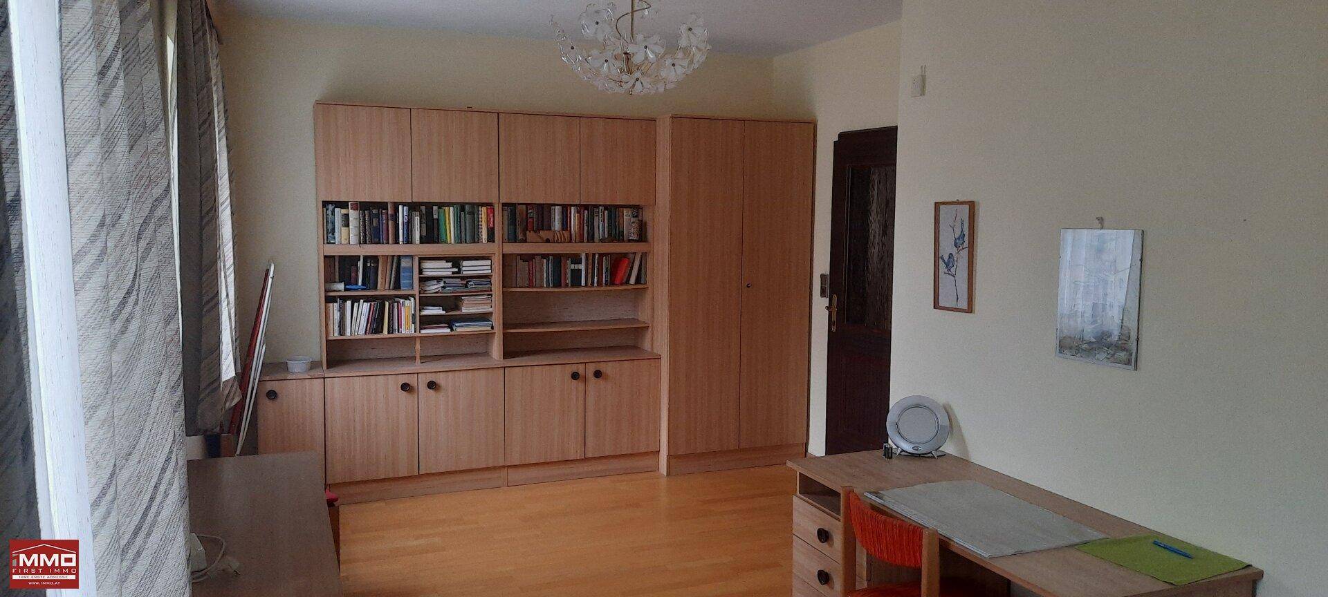 Arbeitszimmer mit großem Schreibtisch, Bücherregalen und Einbauschränken.