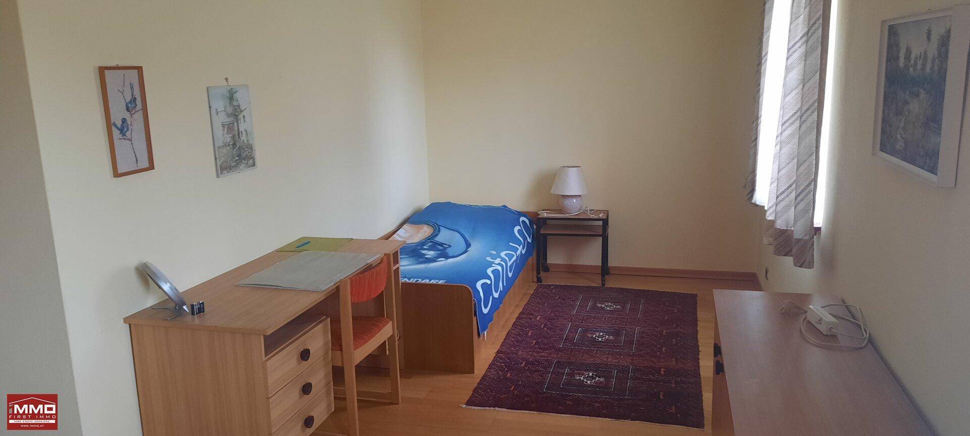 Kinder- oder Gästezimmer mit Einzelbett, Schreibtisch und Holzboden.
