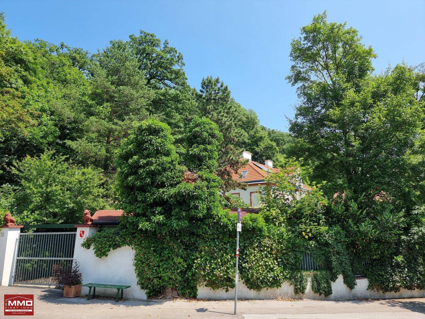 Hausfassade umgeben von üppigem Grün und Bäumen, mit Blick auf die natürliche Umgebung.