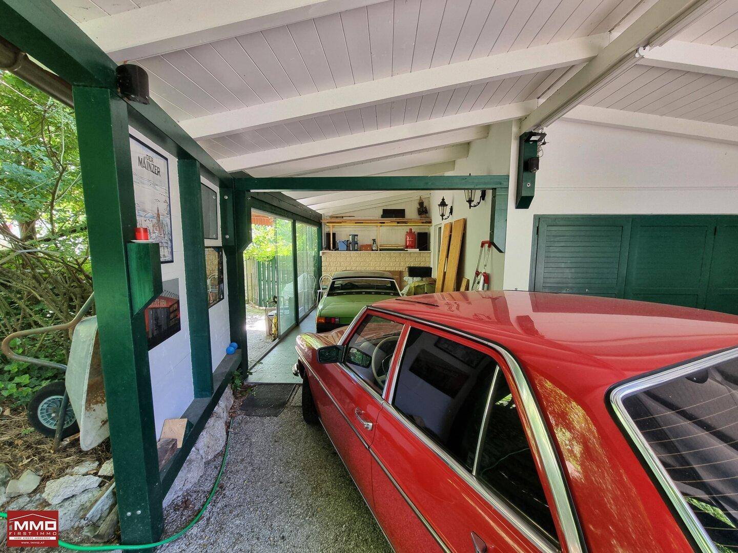 Überdachter Carport mit einem Oldtimer und Zugang zu einem weiteren Bereich des Grundstücks.