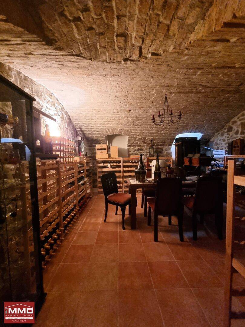 Historischer Weinkeller mit Gewölbedecke, Fliesenboden und rustikalen Weinregalen für Lagerung.