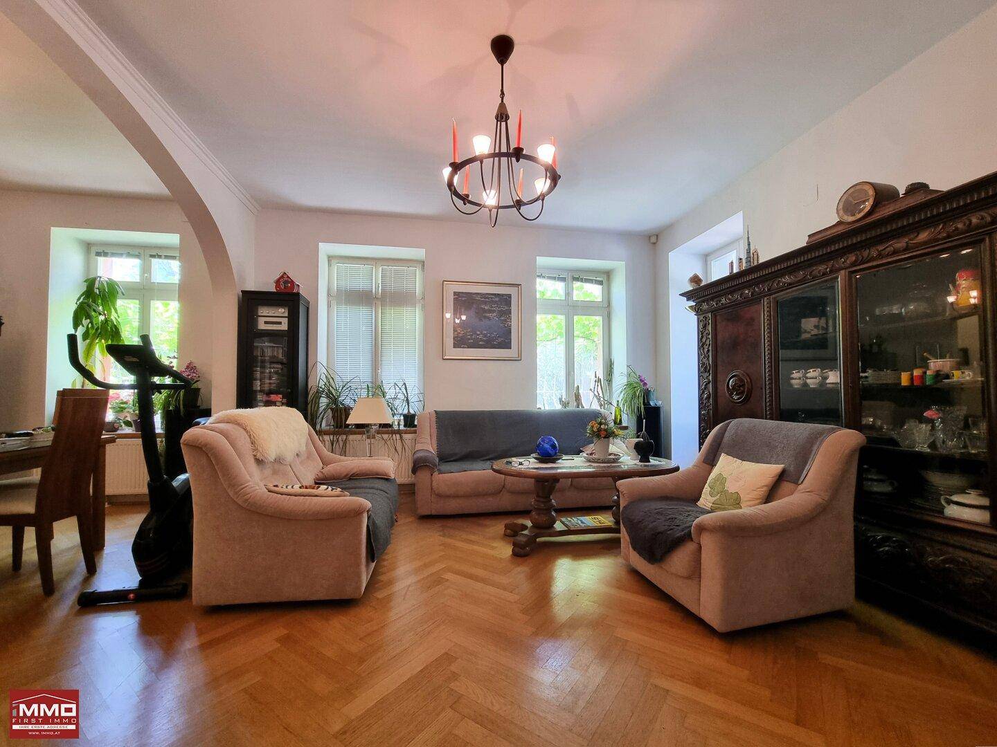Elegantes Wohnzimmer mit Fischgrätparkett, bequemen Sofas und antiken Möbeln.
