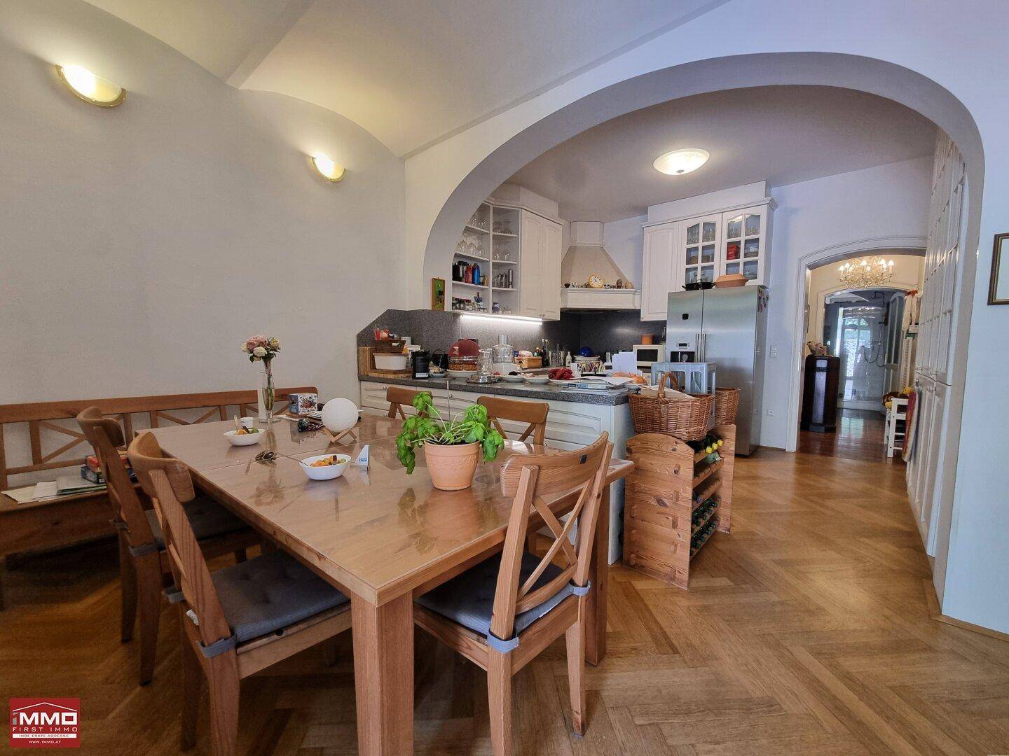 Offener Wohn-Essbereich mit Holztisch, Stühlen und direktem Blick in die angrenzende Küche.