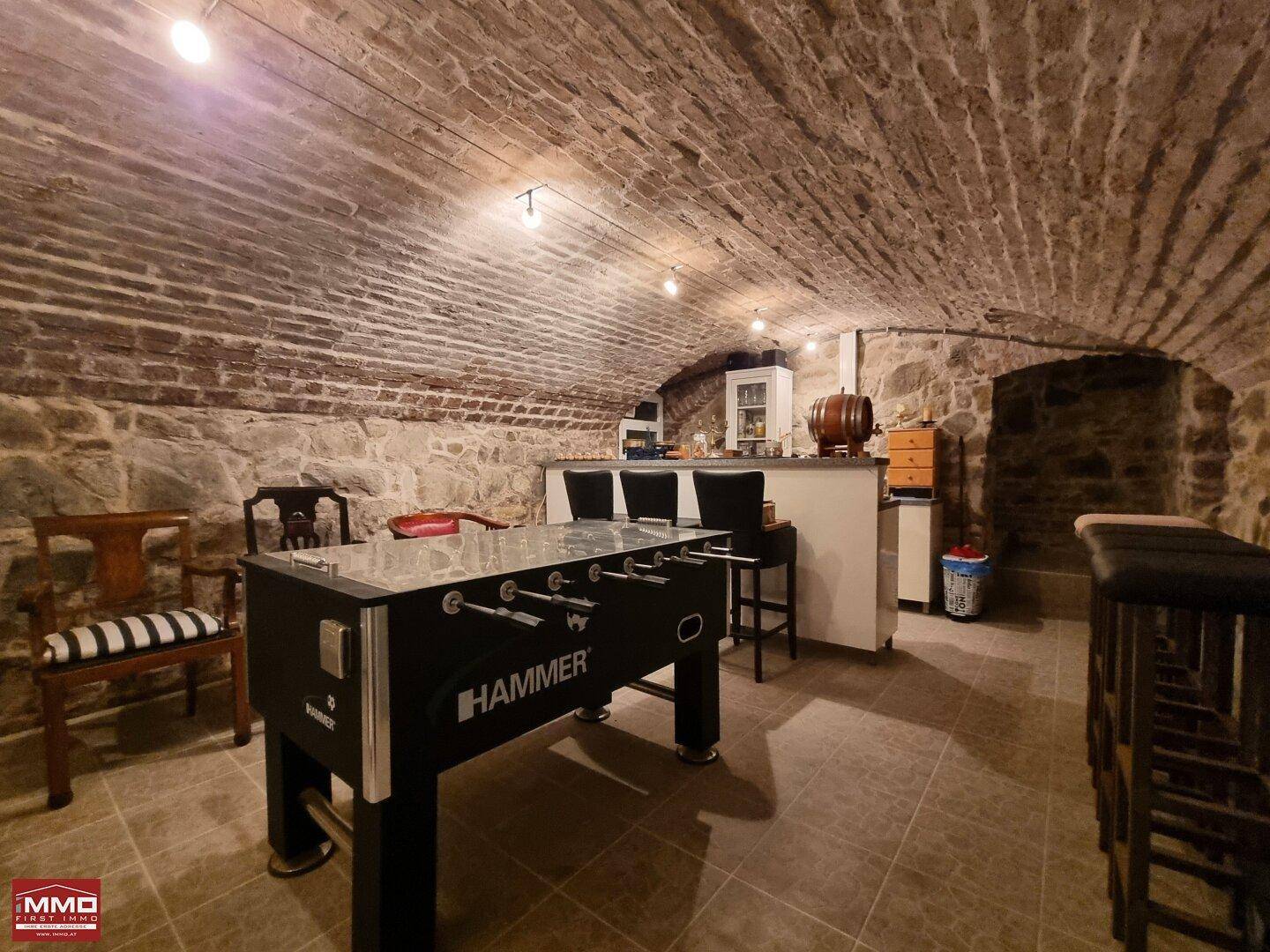 Gemütlicher Kellerraum mit Bar, Sitzgelegenheiten und Tischfußball, perfekt für Unterhaltung.