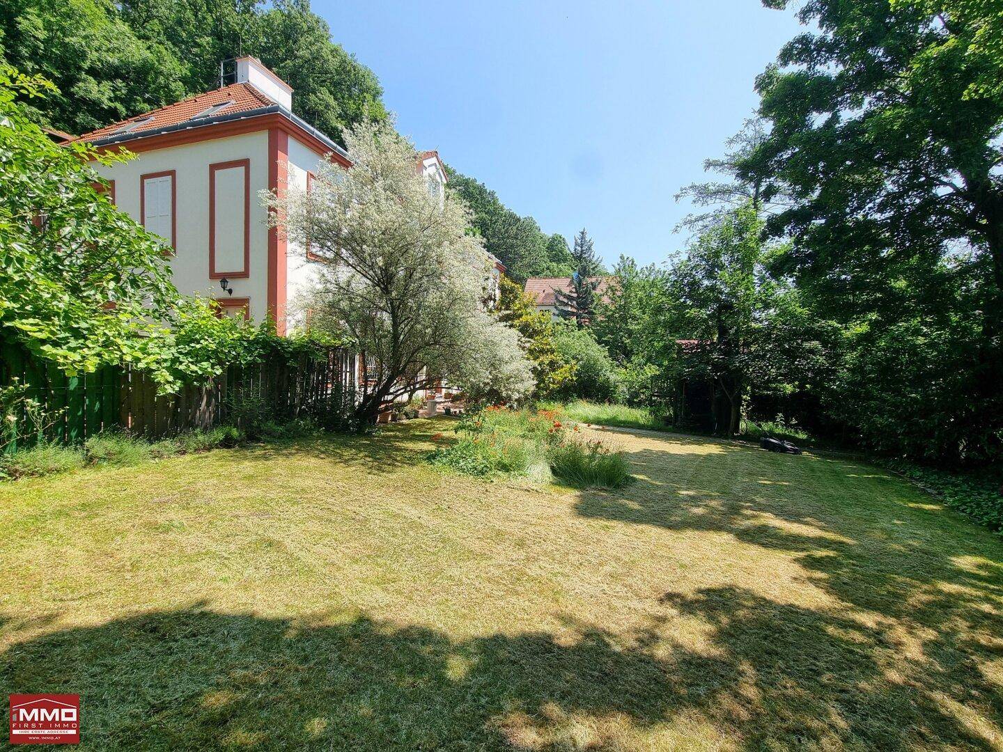 Ausgedehnter Garten mit Rasenfläche und Blick auf die Seitenfassade des charmanten Hauses.