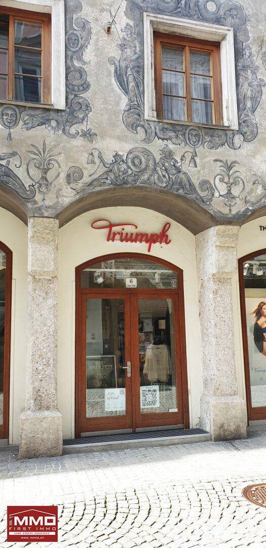 Eingangsbereich eines Geschäfts mit Holztür und steinernen Säulen unter der historischen Fassade.