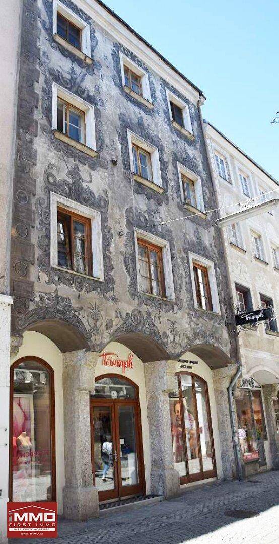 Historisches Gebäude mit aufwendig bemalter Fassade und Geschäftsflächen im Erdgeschoss.