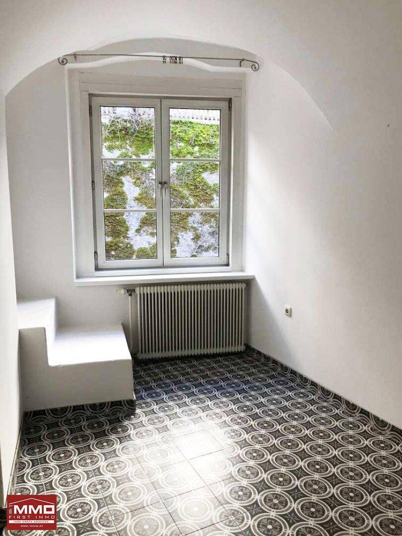 Heller Raum mit gemusterten Fliesen, Fenster und einer eingebauten Sitzbank.