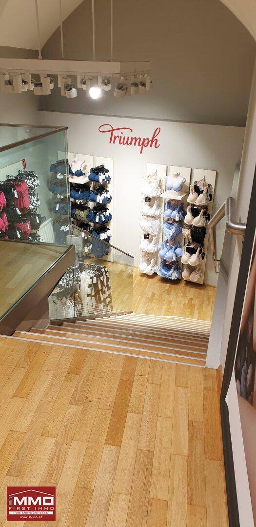 Blick von der Treppe in den Verkaufsraum mit Holzboden und Auslagen.