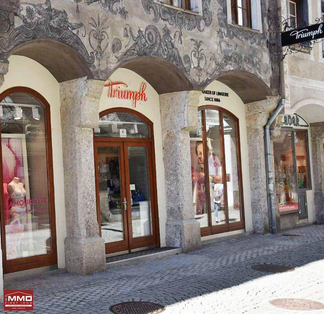 Detailansicht der historischen Fassade mit Arkaden und modernen Schaufenstern im Erdgeschoss.