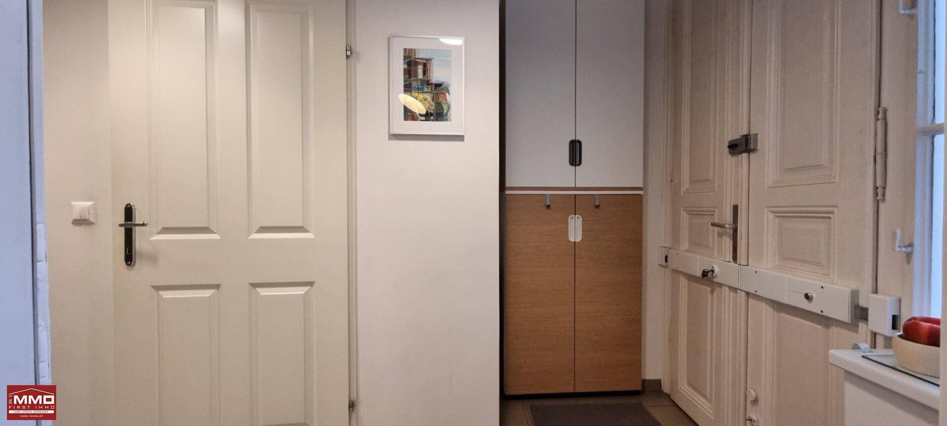 Flur mit mehreren weißen Türen und einem schmalen Holzschrank.