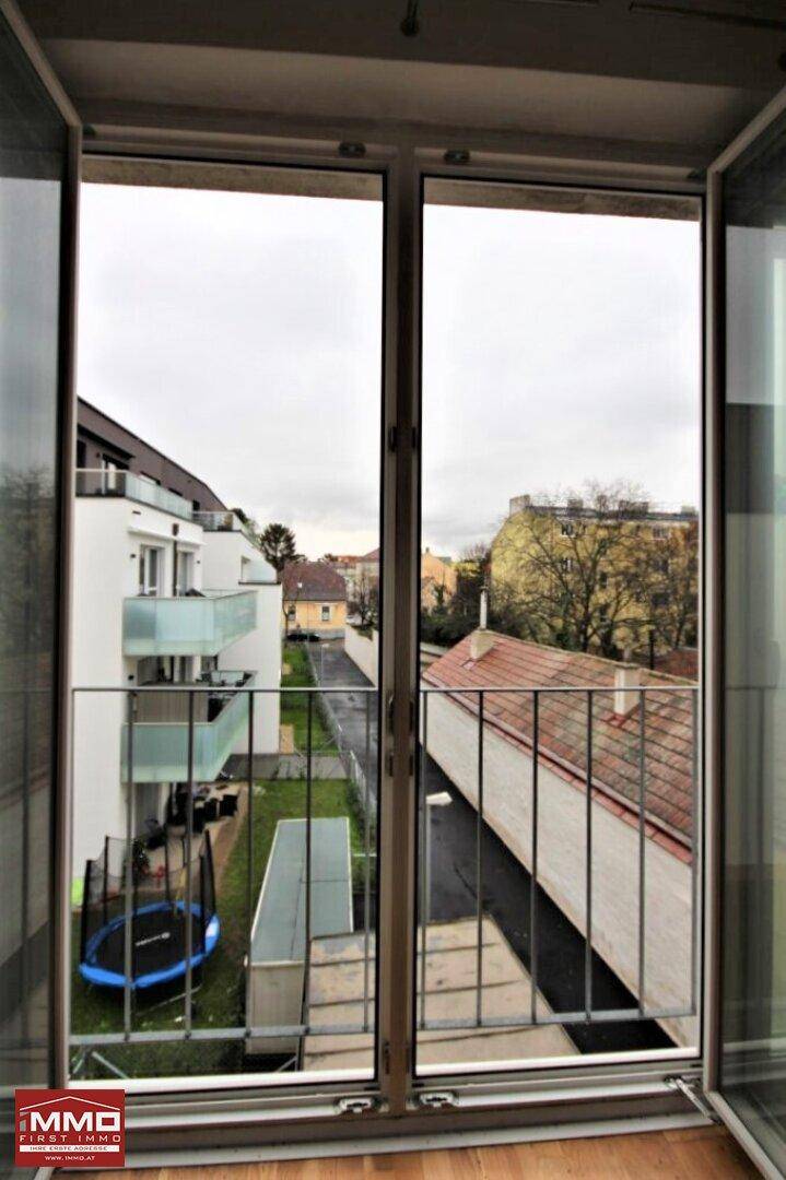 Blick aus dem Fenster auf den grünen Gemeinschaftsgarten mit Trampolinen.