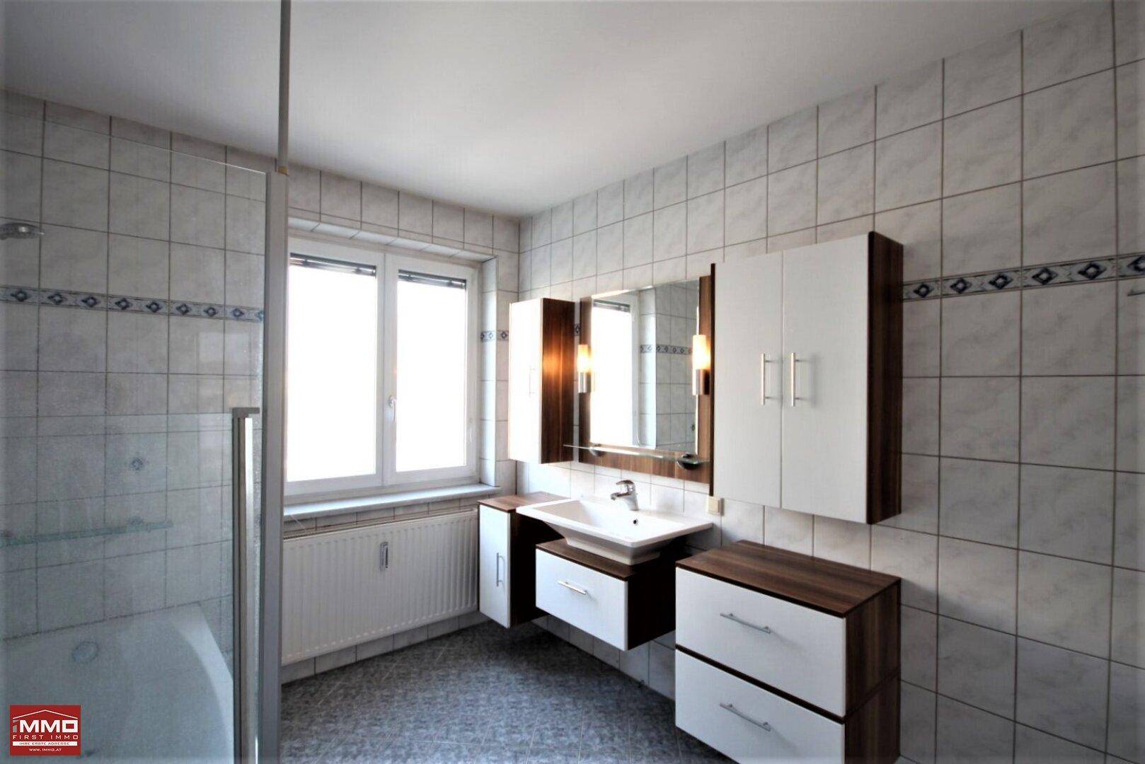 Modernes Badezimmer mit Badewanne, Duschfunktion, Einzelwaschbecken und Fenster.
