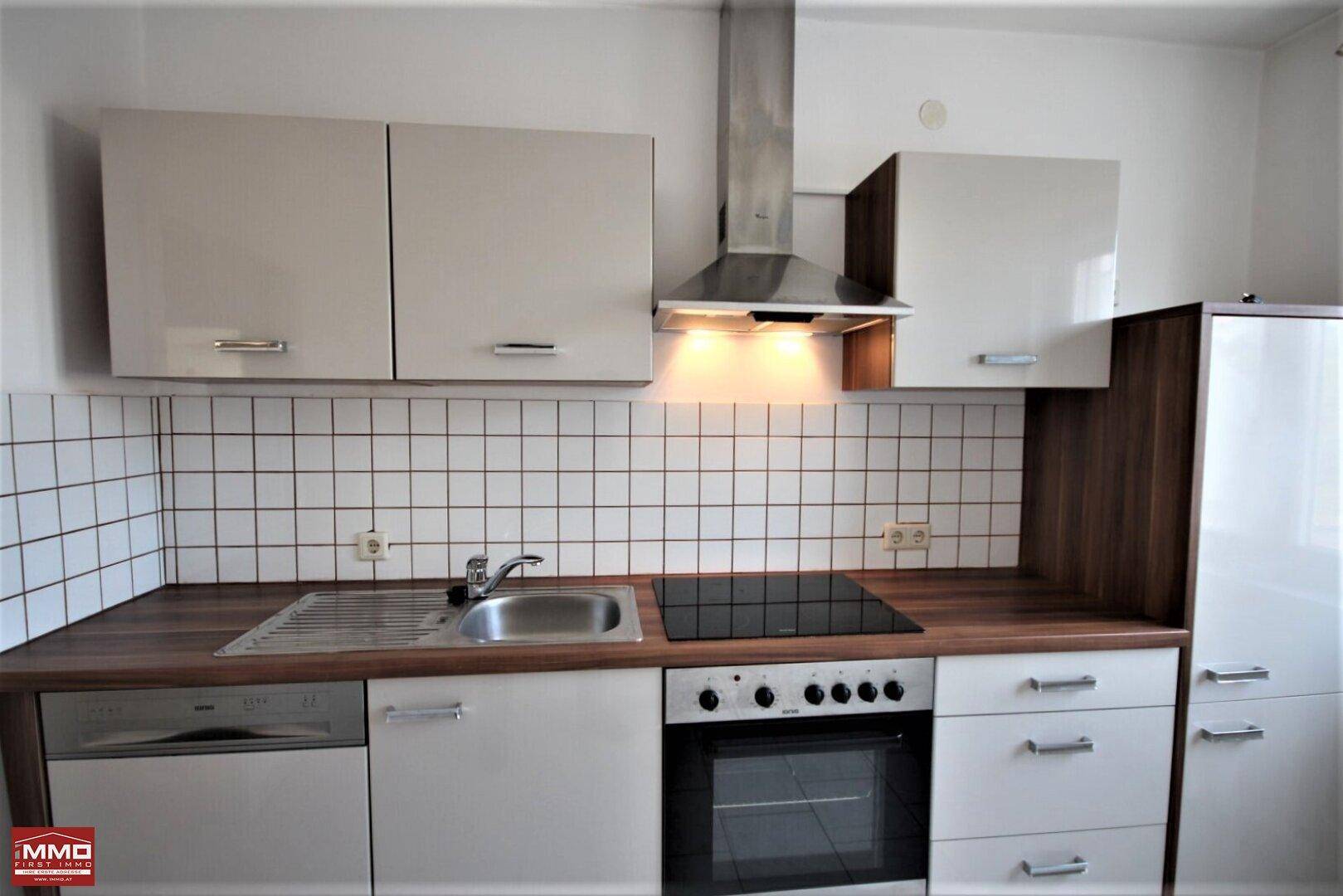 Moderne Einbauküche mit Induktionskochfeld, Backofen, Geschirrspüler und Dunstabzugshaube.
