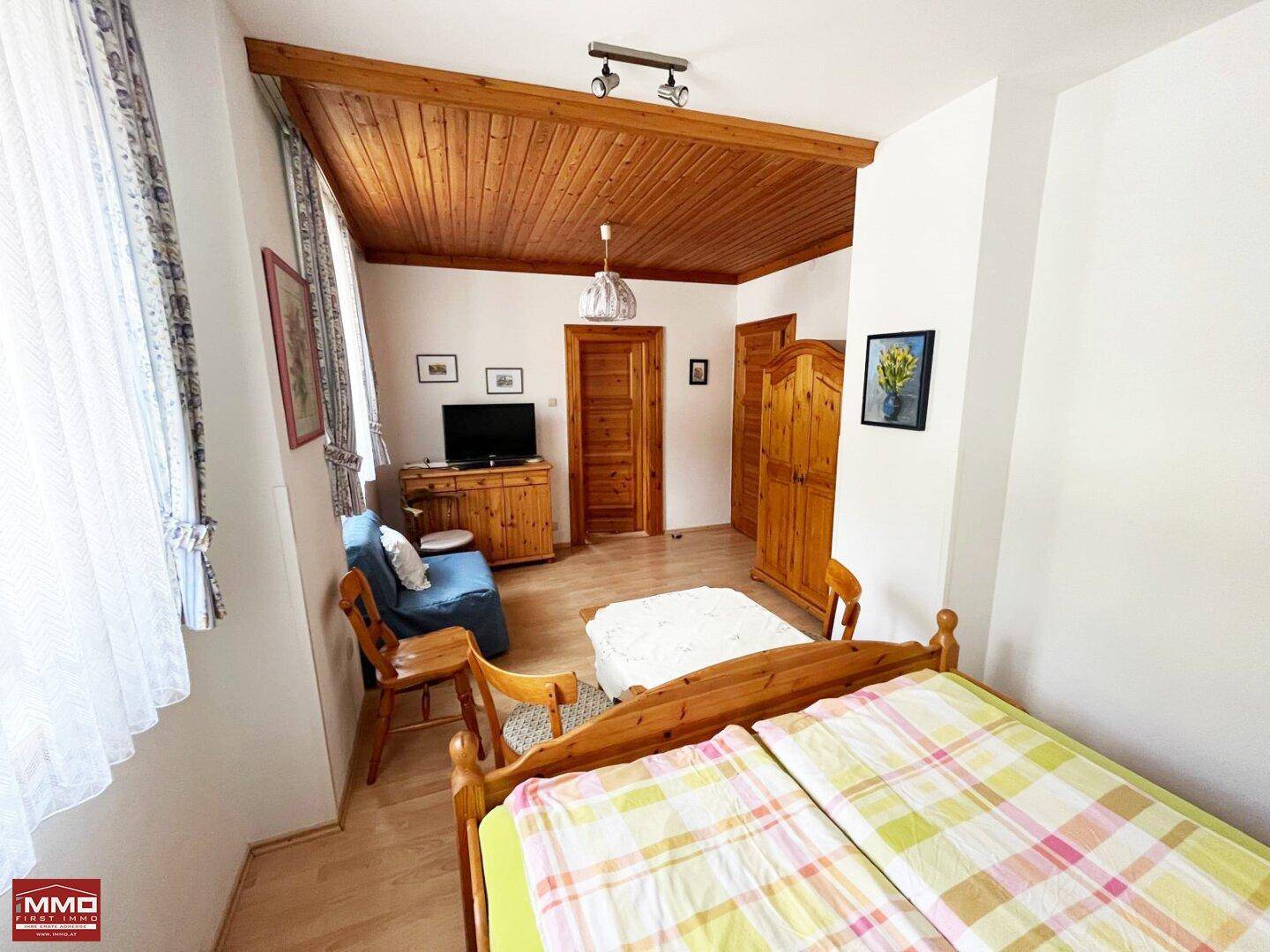 Gemütliches Schlafzimmer mit Holzboden, Holzbalken und traditionellen Holzmöbeln.