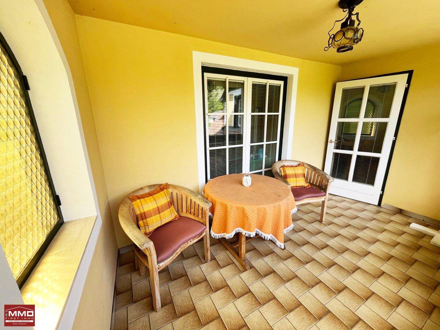 Überdachter Balkon mit Fliesenboden und Sitzgelegenheiten, ideal für entspannte Stunden.