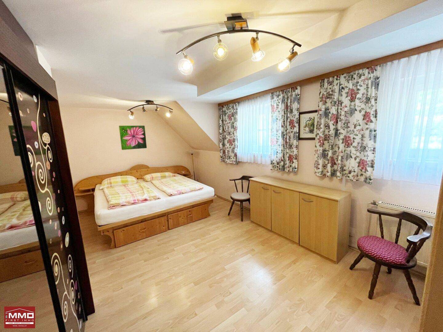 Gemütliches Schlafzimmer im Dachgeschoss mit Holzboden, Dachschrägen und Doppelbett.