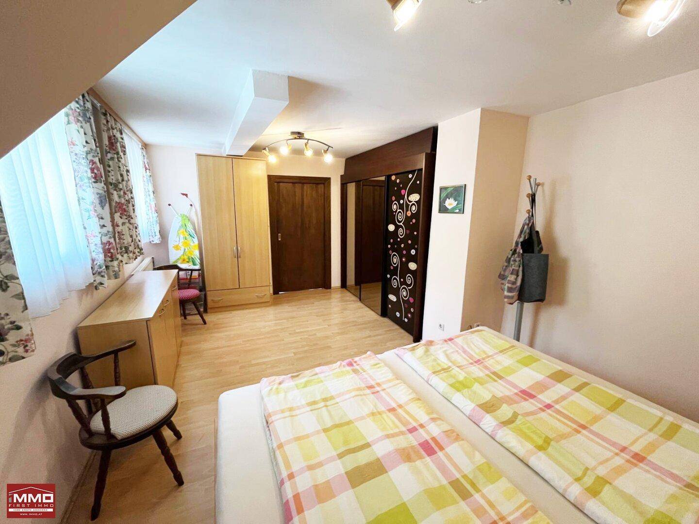 Helles Schlafzimmer im Dachgeschoss mit Holzboden, Dachschrägen und Kleiderschrank.