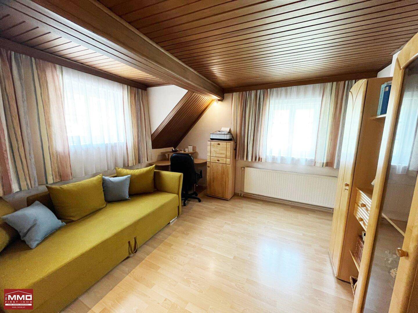 Arbeitszimmer mit Holzboden, Holzbalkendecke und einem Schlafsofa, ideal für Gäste.