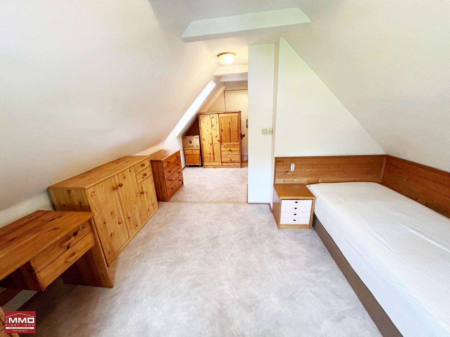 Geräumiges Schlafzimmer im Dachgeschoss mit Teppichboden, Dachschrägen und viel Stauraum.