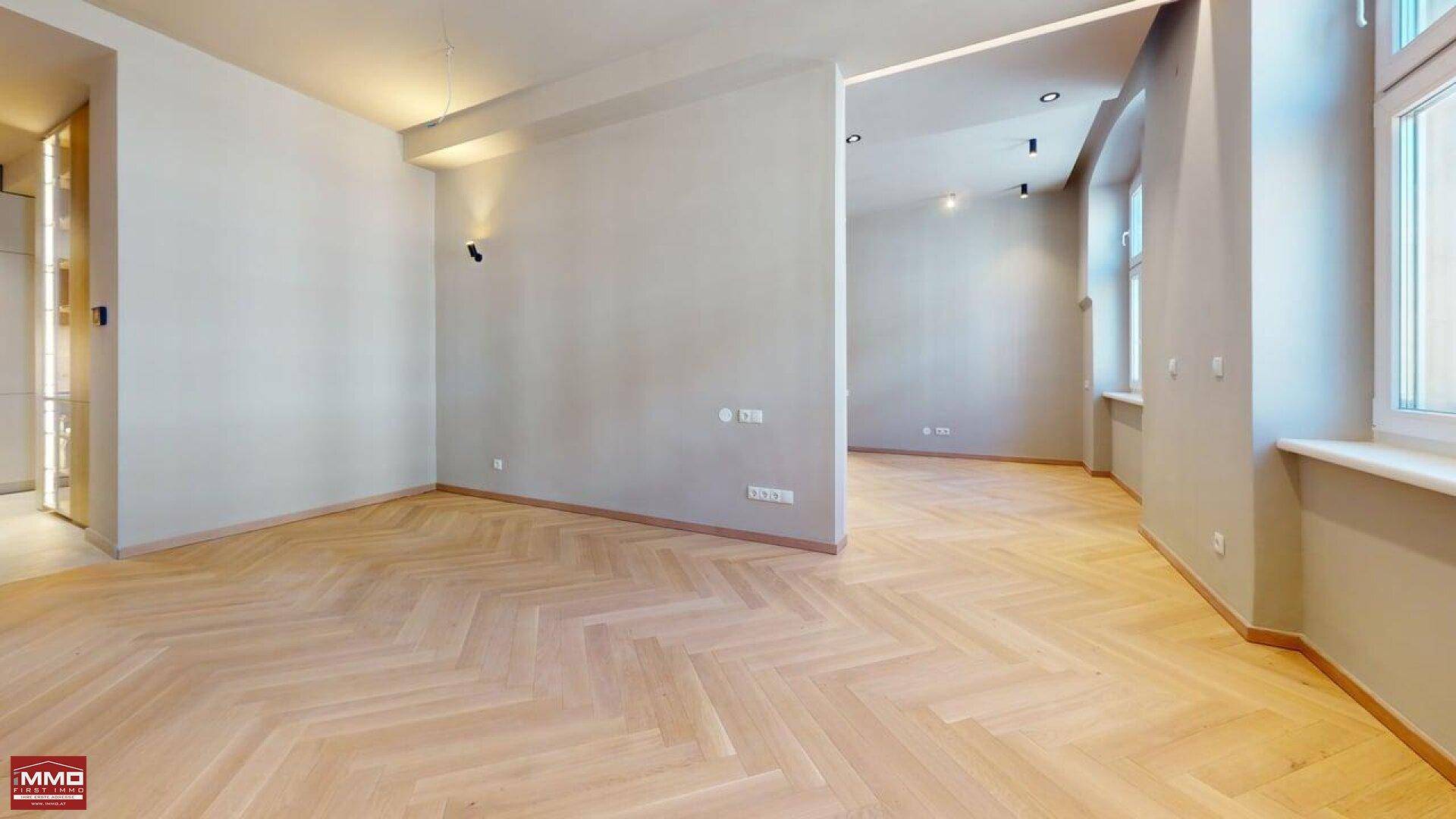 Helles Wohnzimmer mit stilvollem Fischgrätparkett und großen Fenstern, bereit zum Einrichten.