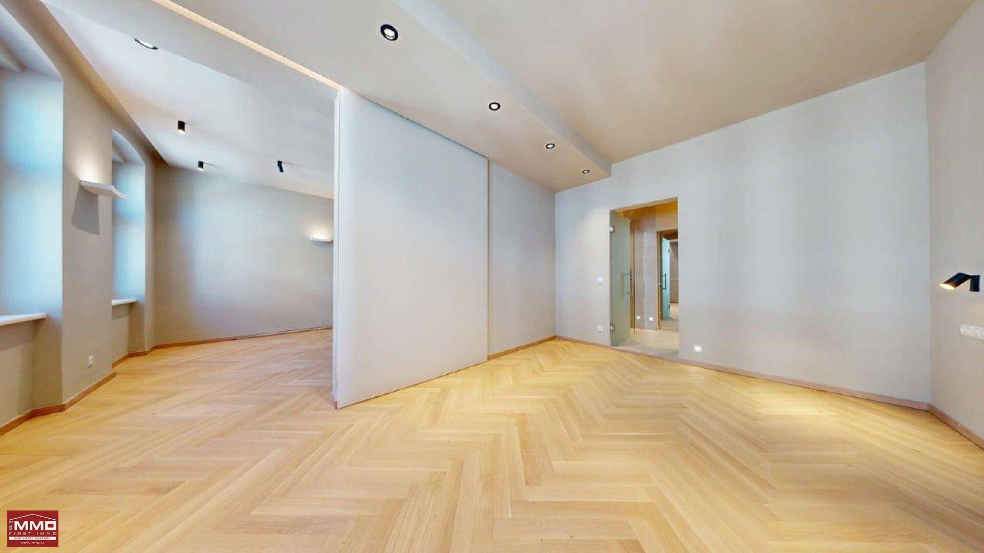 Modernes Wohnzimmer mit Fischgrätparkett, Einbaustrahlern und einer eleganten Schiebetür.