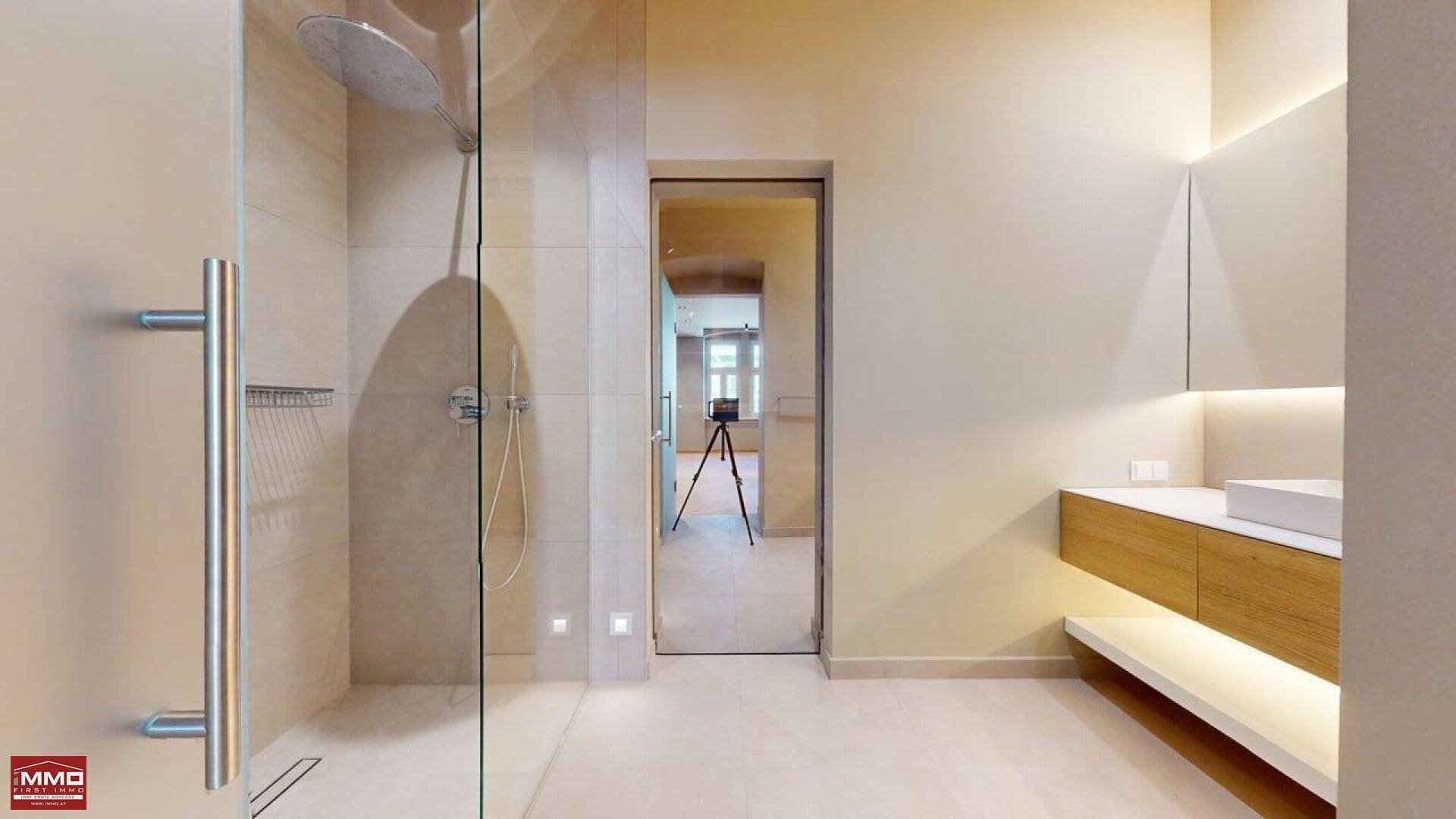 Modernes Badezimmer mit begehbarer Regendusche, schwebendem Waschtisch und eleganten Fliesen.