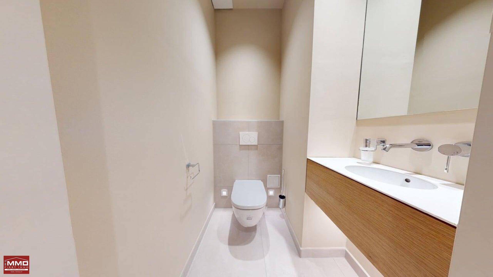 Modernes Gäste-WC mit wandhängender Toilette, schwebendem Waschtisch und eleganten Fliesen.