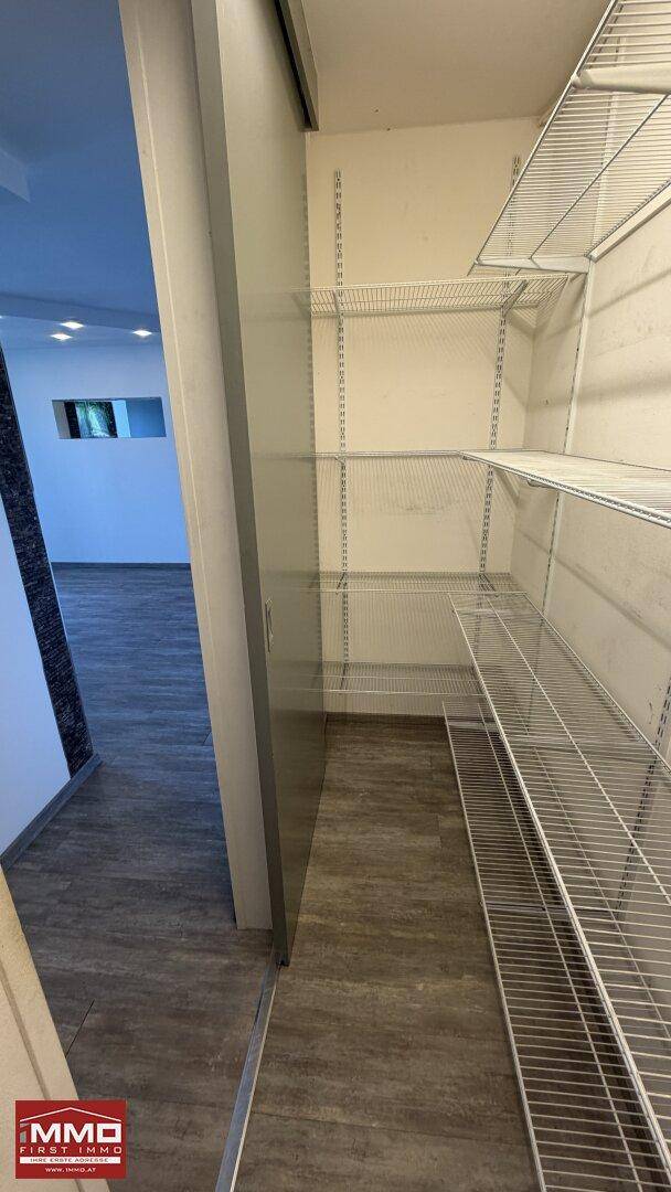 Praktischer Abstellraum mit Drahtregalen und Holzoptikboden für zusätzlichen Stauraum.
