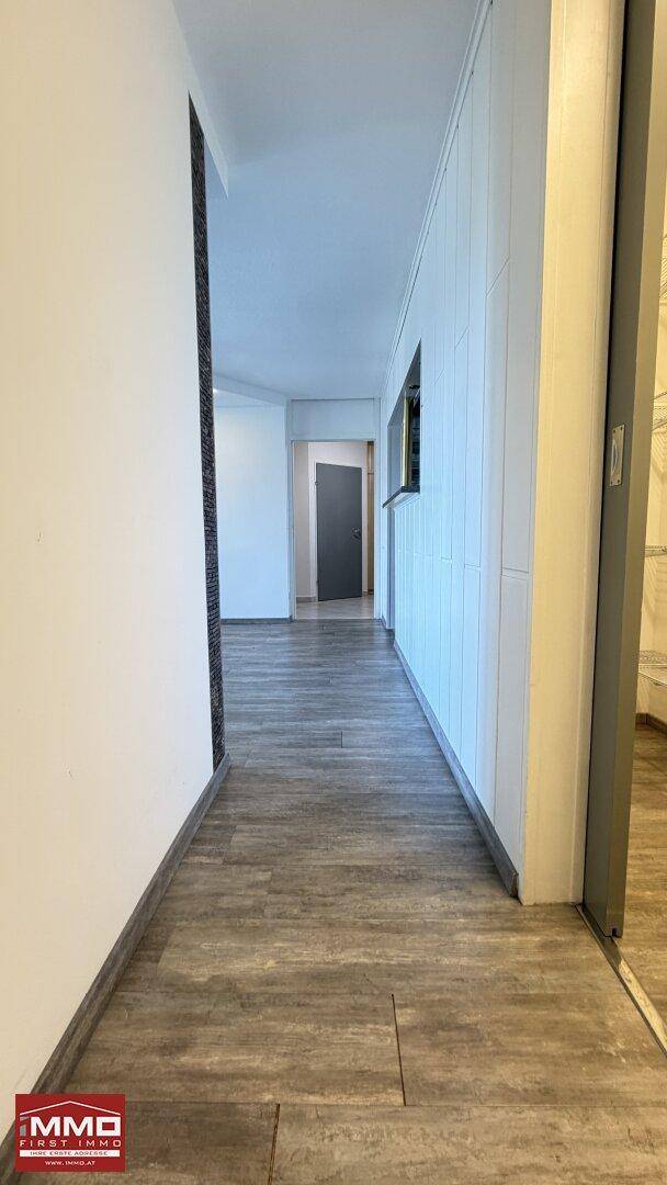 Langer, heller Flur mit modernem Holzoptikboden, der zu weiteren Räumen führt.
