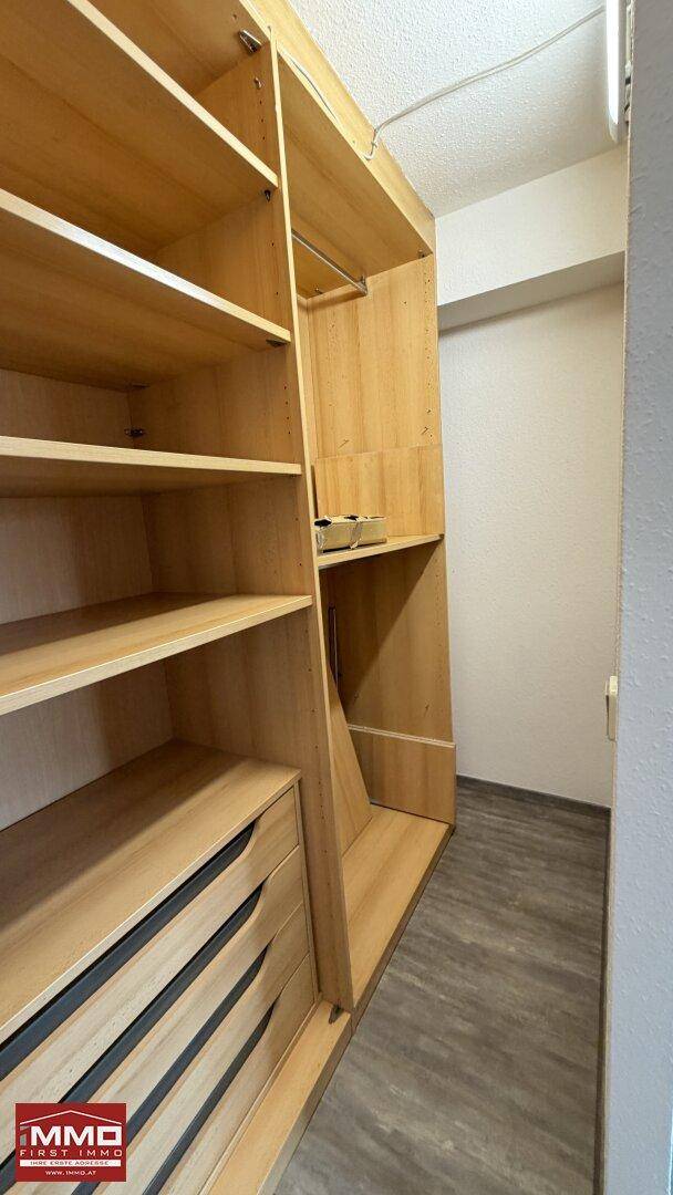 Begehbarer Kleiderschrank mit Holzregalen und viel Platz zum Aufhängen von Kleidung.