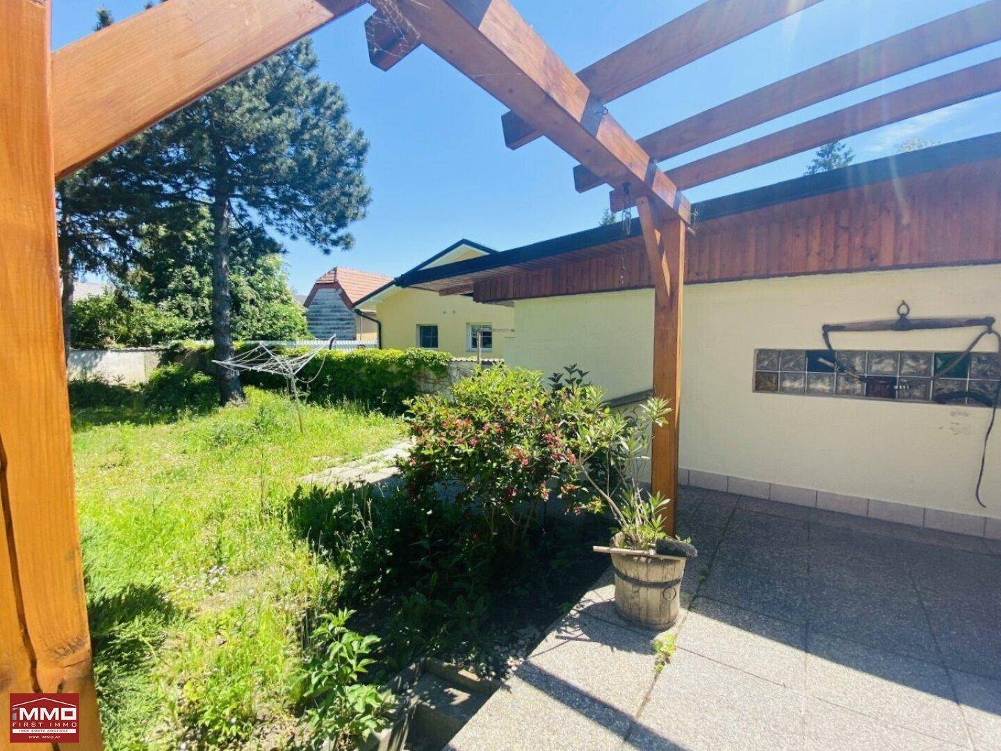 Blick von der Terrasse in den weitläufigen Gartenbereich mit Rasenfläche und Sträuchern.