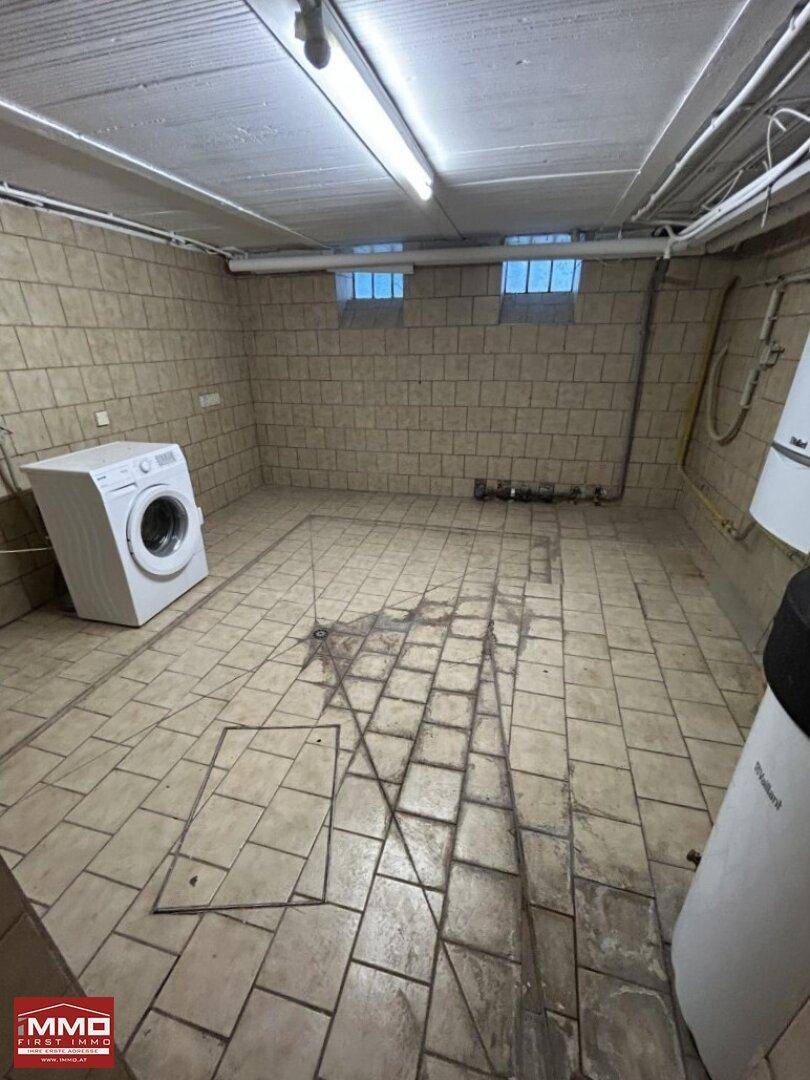 Gefliester Kellerraum mit Waschmaschine und Heizungsanlage, ideal als Hauswirtschaftsraum.