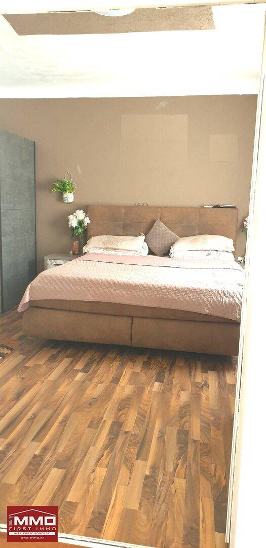 Schlafzimmer mit Doppelbett und Holzboden, die Wände sind in einem warmen Braunton gestrichen.
