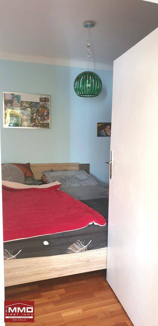 Schlafzimmer mit Doppelbett und Holzboden, die Wände sind in einem hellen Blauton gehalten.