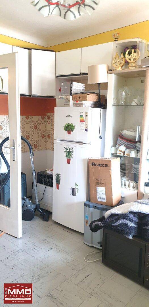 Küche oder Hauswirtschaftsraum mit Kühlschrank, Schränken und einem Staubsauger.