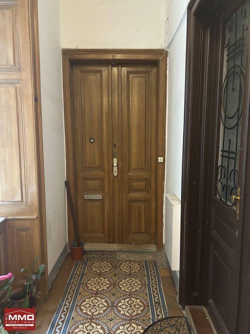 Massive Holztür mit dekorativen Fliesen im Eingangsbereich einer Wohnung oder eines Altbaus.