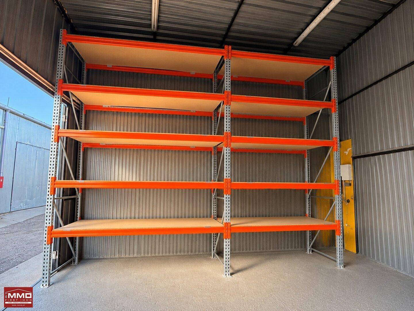 Lagerbereich mit robusten Metallregalen an der Wand, Wellblechverkleidung und Betonboden.
