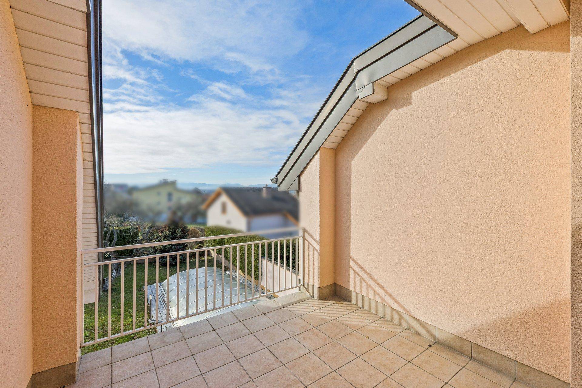 Gefliester Balkon mit Geländer und weitem Blick über die umliegende Landschaft und Häuser.