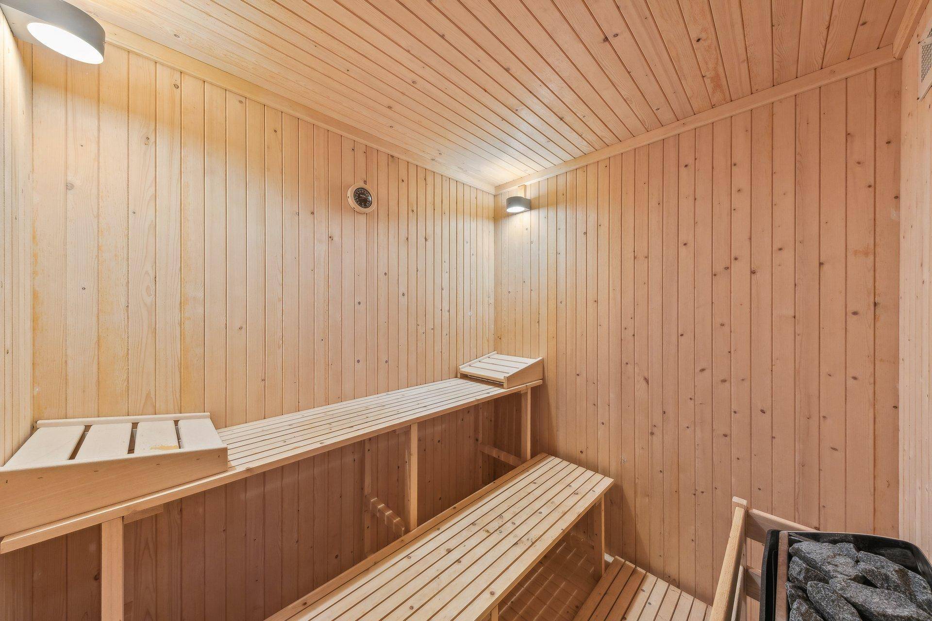 Holzvertäfelte Sauna mit mehreren Bänken und einem Saunaofen, ideal für Wellness und Entspannung.