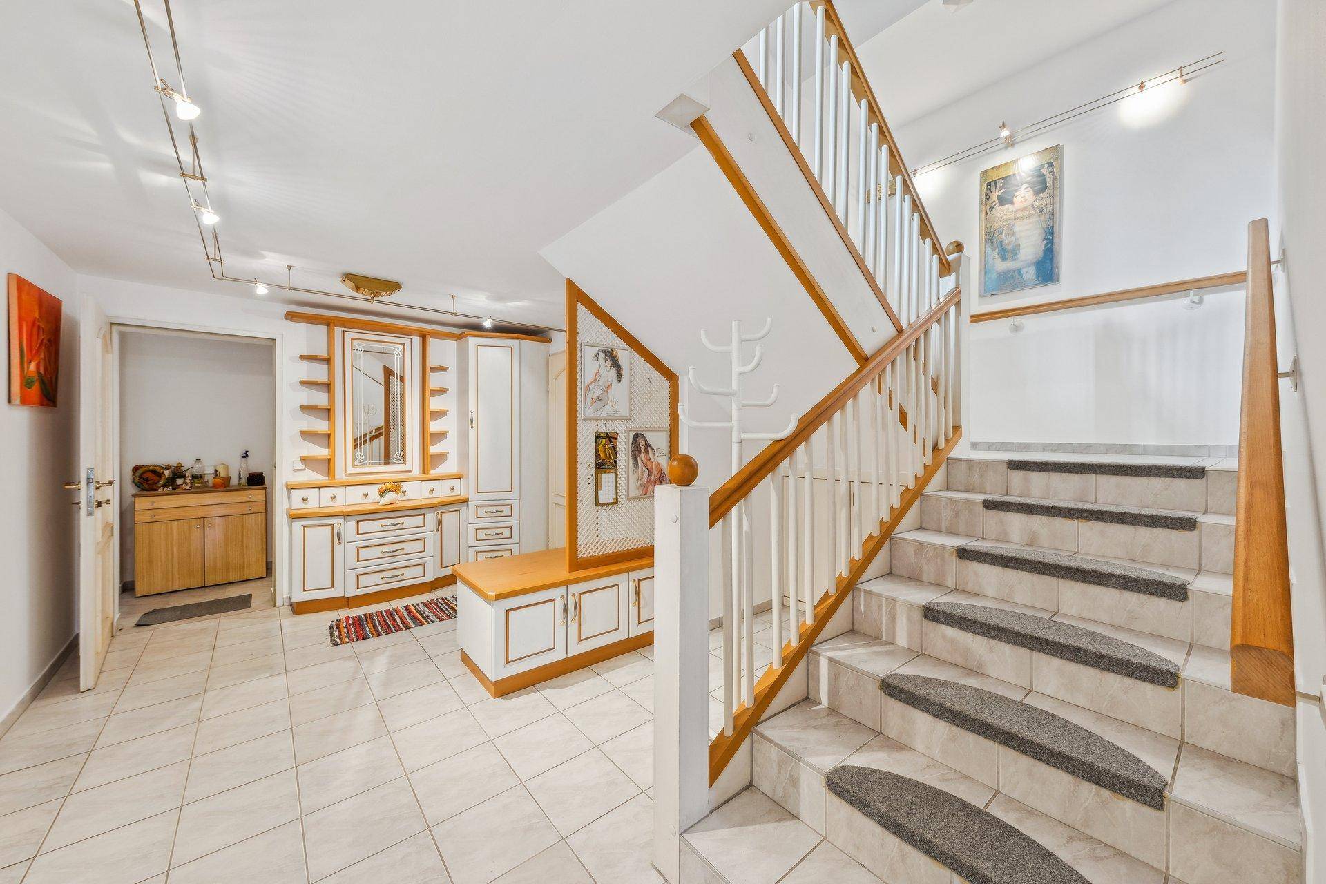Geräumiger Eingangsbereich mit Fliesenboden, einer Holztreppe und praktischen Einbauschränken.