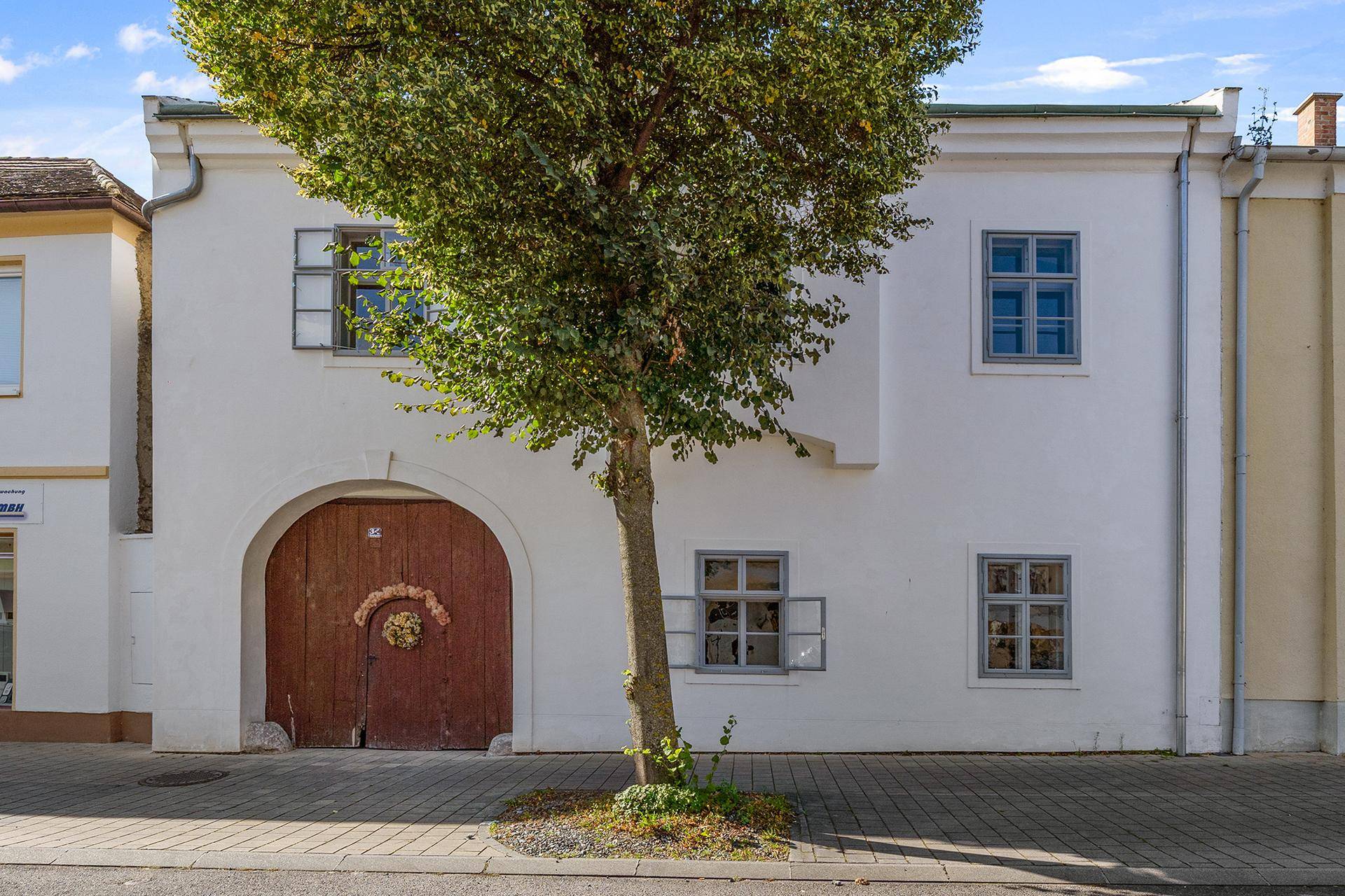 Historische Fassade des Gebäudes mit Holztor und traditionellen Fenstern an der Straße.