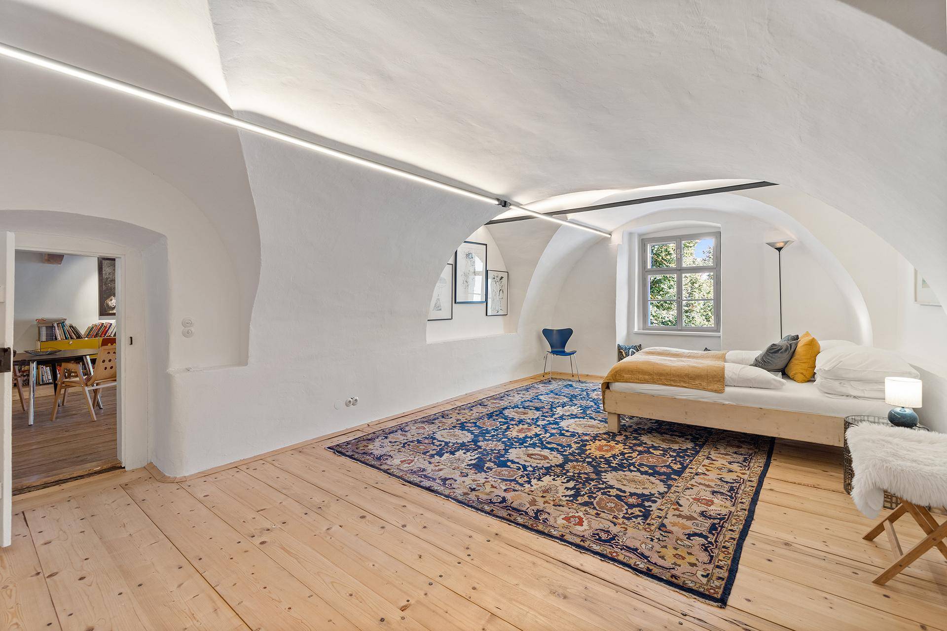 Geräumiges Schlafzimmer mit Gewölbedecke, Holzdielenboden und großem Orientteppich.