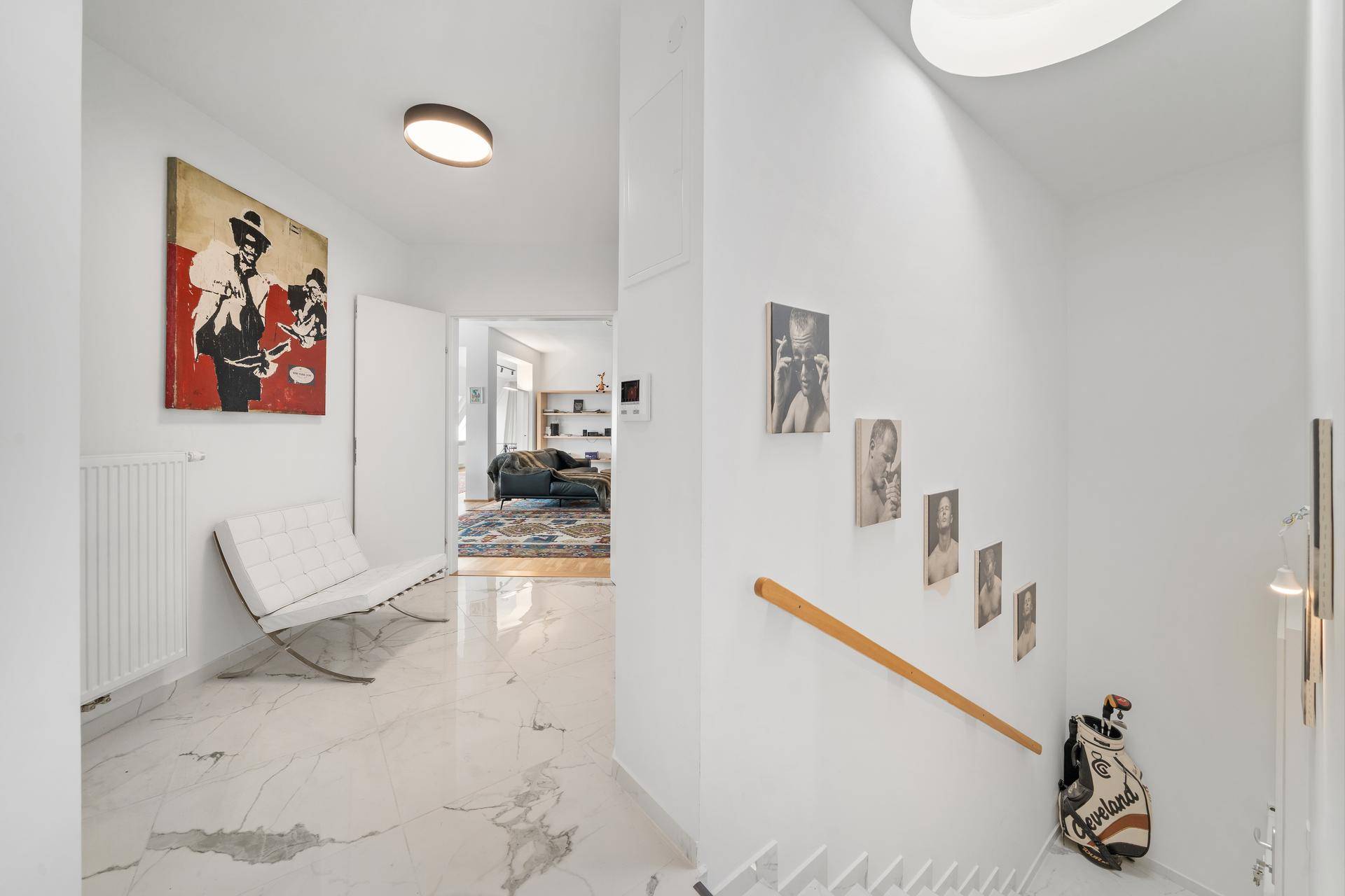 Heller Flur mit Marmorboden, Treppe und Kunstwerken an den Wänden.