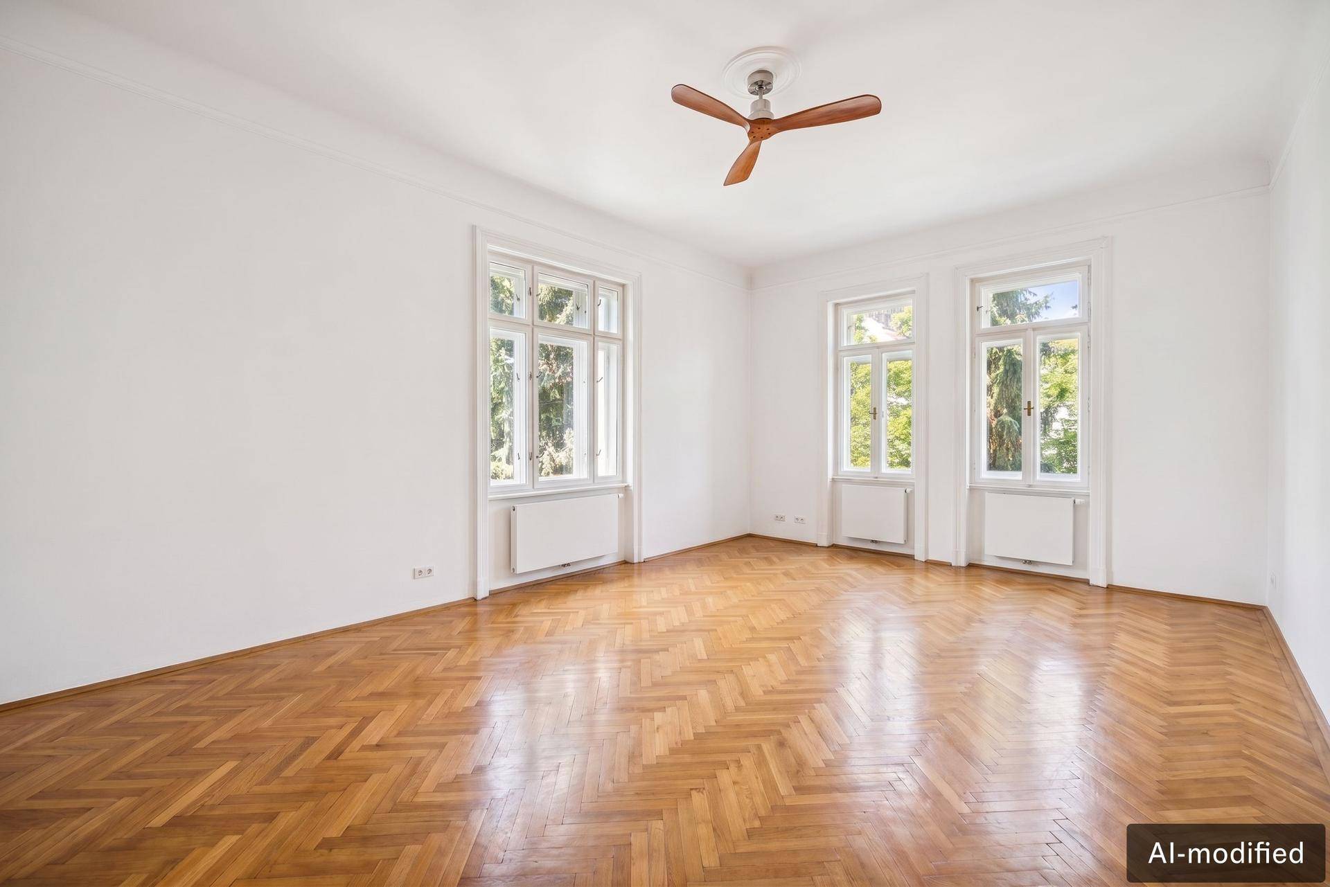 Helles Wohnzimmer mit Fischgrätparkett, hohen Decken und großen Fenstern.