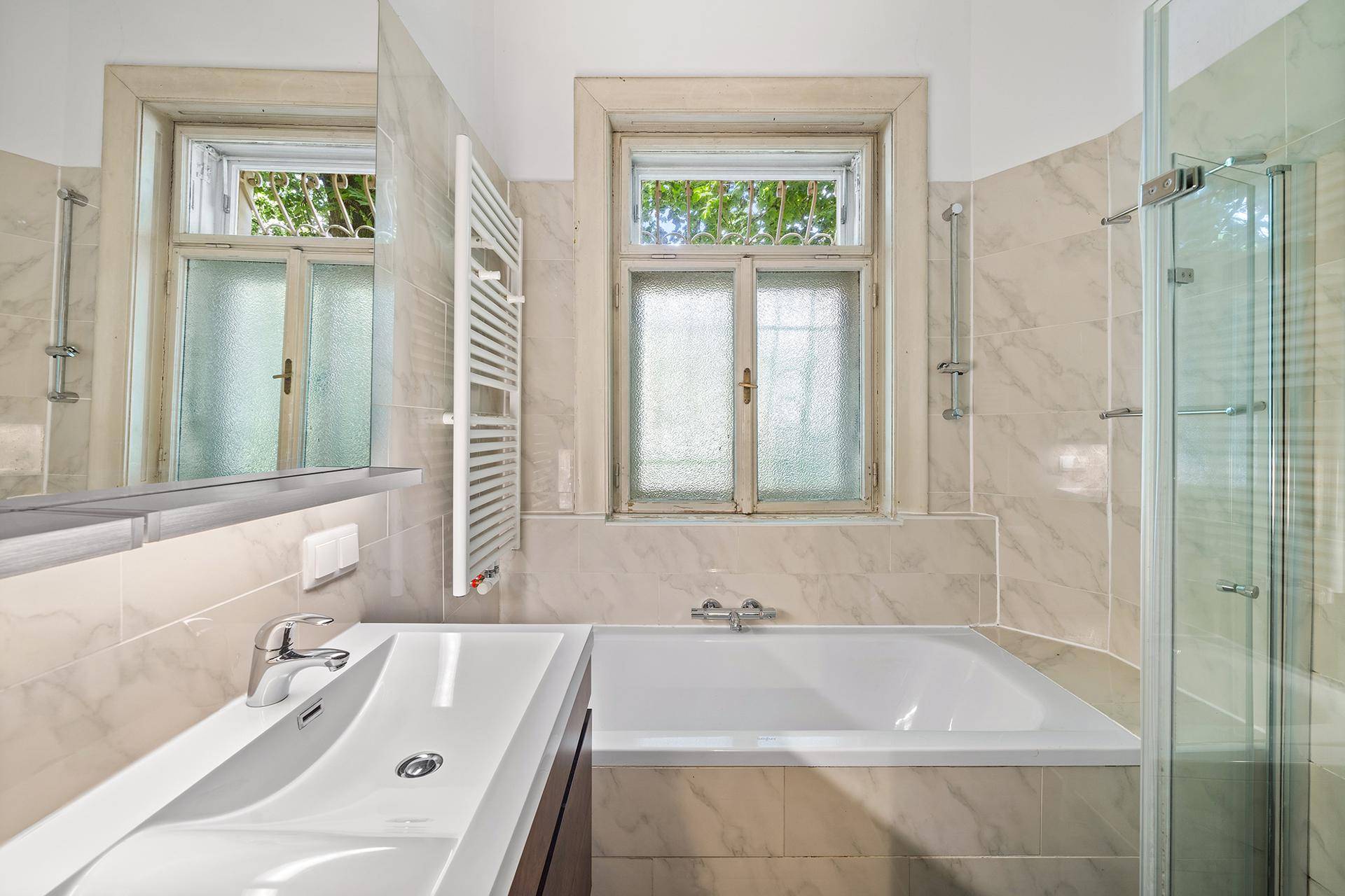 Modernes Badezimmer mit Badewanne, Dusche, Einzelwaschbecken und Fenster.